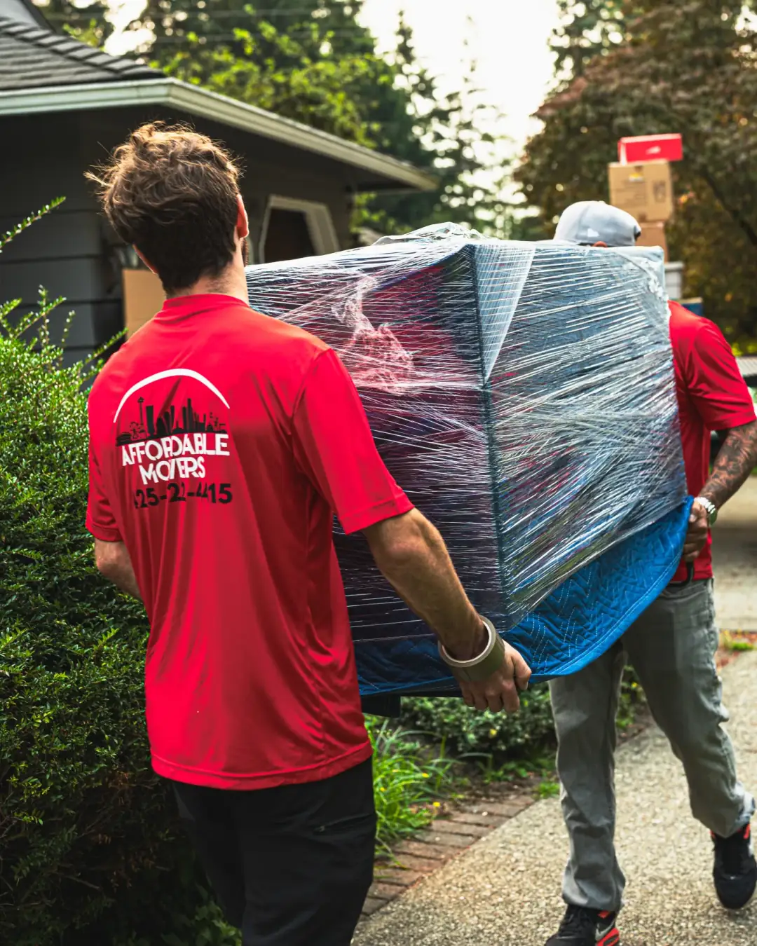 Affordable Movers crew carrying protected furniture from a home.